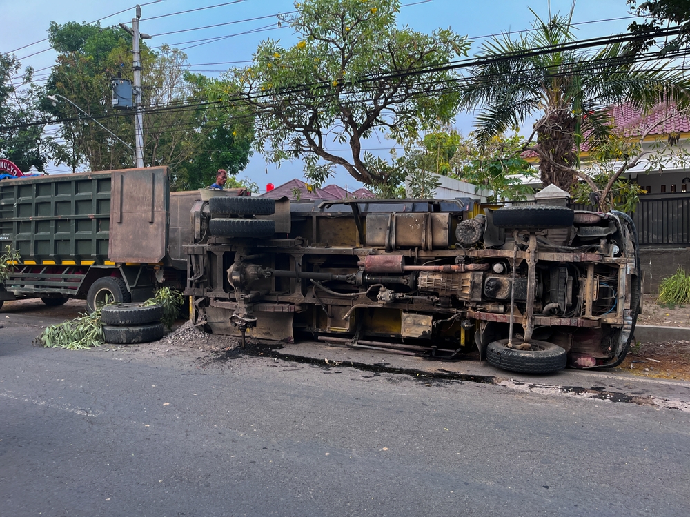 Overturned box truck on city street with debris